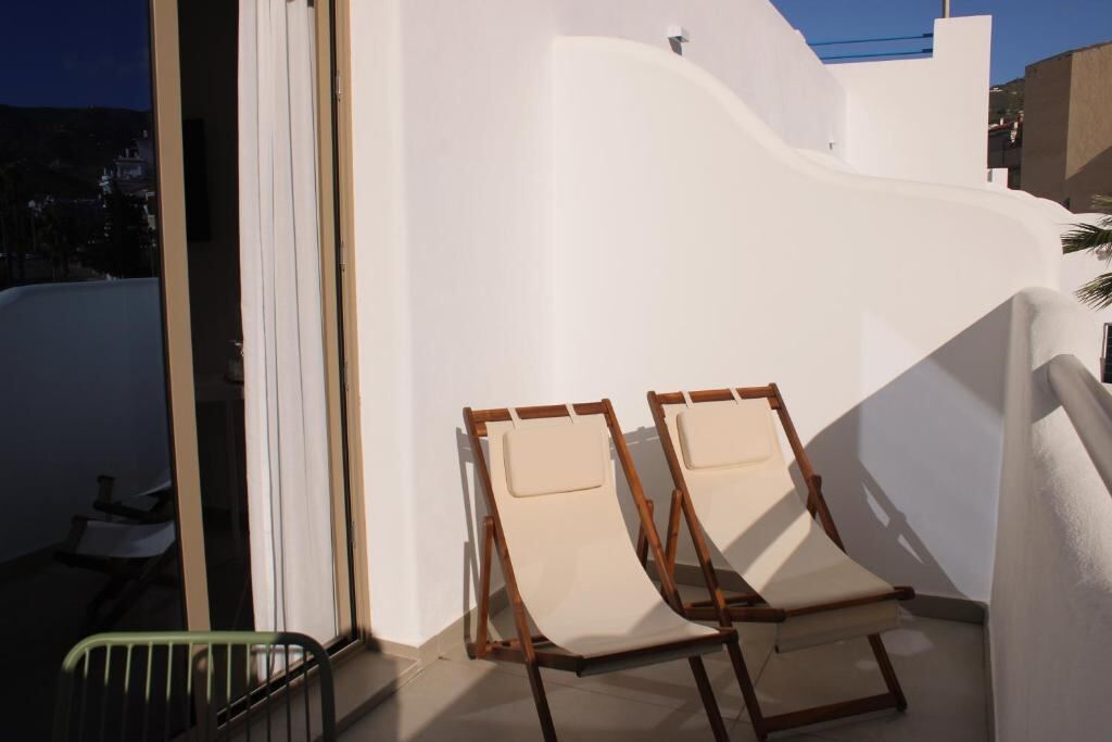 Two sun loungers on a private white balcony